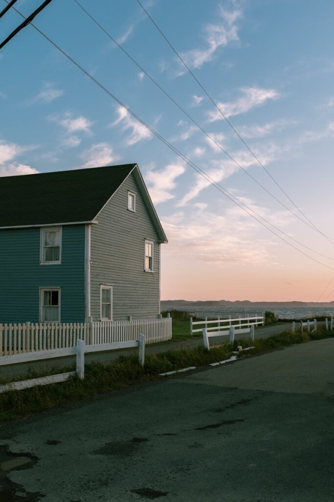 a blue house sitting next to a white fence