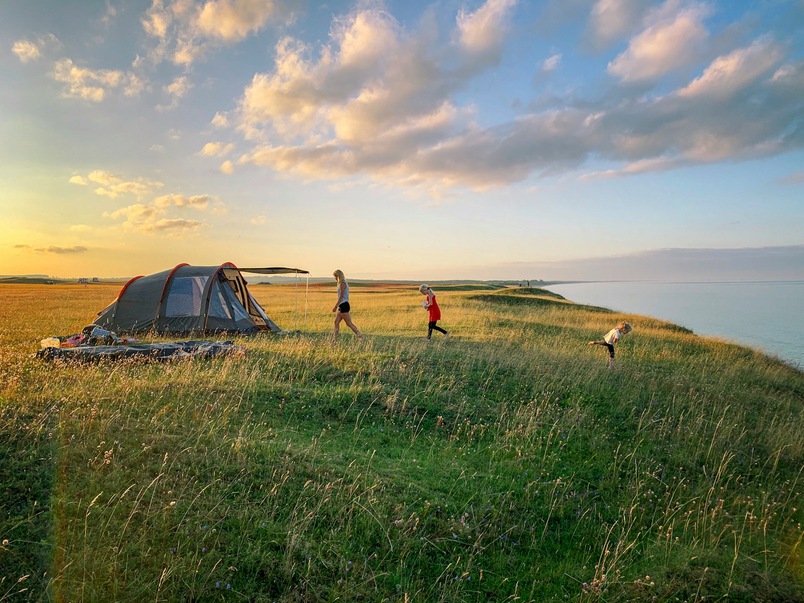 toddler walking on green grass with set-up tent during golden hour