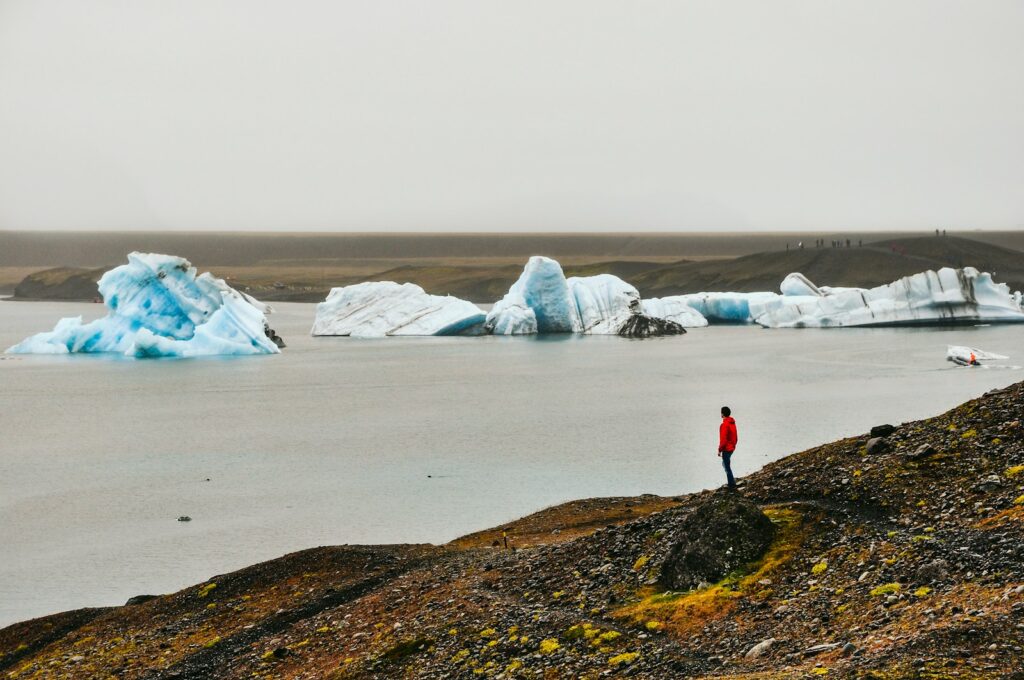 a man standing on top of a hill next to a body of water