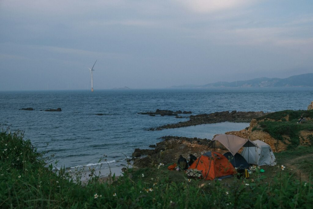 Tents pitched by the sea with a lightning strike.